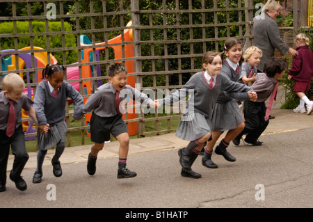 Kinder in einer Linie, die Hand in Hand laufen auf dem Spielplatz der Schule Stockfoto