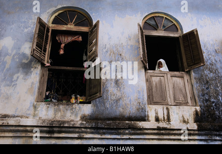 Junges Mädchen Blick aus Fenster einer Wohnung in Stonetown, Sansibar, Tansania, Ostafrika. Amyn Nasser amynnasser Stockfoto