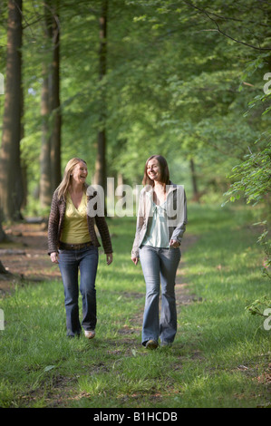 Zwei junge Frauen, die zu Fuß durch Wald Stockfoto