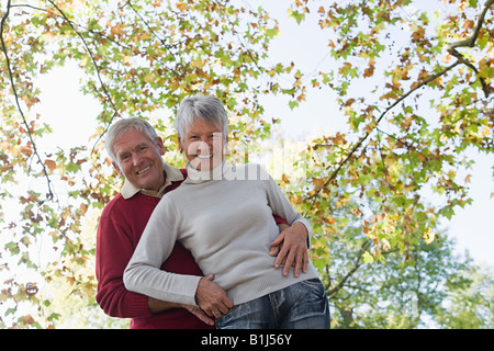 Älteres paar umarmt in der Nähe von Bäumen Stockfoto