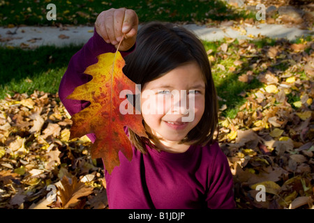 Junges Mädchen hält Eichenblatt drehen Farben im Herbst in Idaho USA Stockfoto