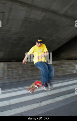 männlichen Teenager im Erdgeschoss mit seinem Skateboard springen Stockfoto