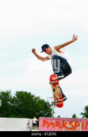 männlichen Teenager mit seinem Skateboard über eine Halfpipe springen Stockfoto