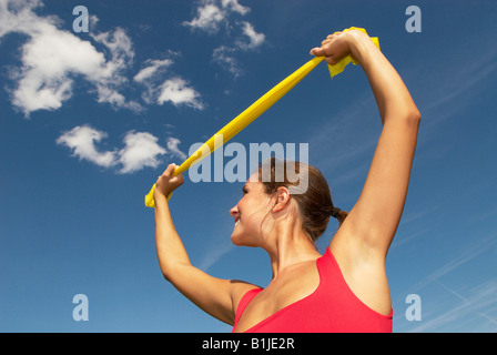 junge Frau, die Übungen mit einem Stretch-Band auf einer Wiese Stockfoto
