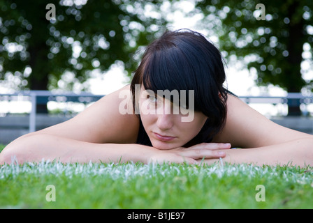 junge Frau mit Sport Kleid auf einer Wiese erschöpft liegend Stockfoto