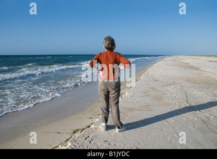 Frau genießt einen morgendlichen Spaziergang entlang des Strandes an der St. George Island State Park Florida Stockfoto