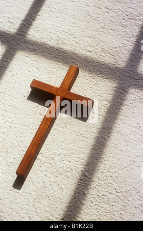 Nahaufnahme eines kleinen einfachen plain Holz Kruzifix liegen im Sonnenlicht auf weiß lackiertem strukturierte Fensterbank mit Schatten in Anlehnung an Kreuz Stockfoto