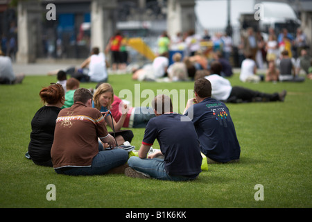 Gruppe von jungen Erwachsenen Freunde sitzen mit Mittagessen auf dem Rasen in Nordirland Belfast City Hall Stockfoto