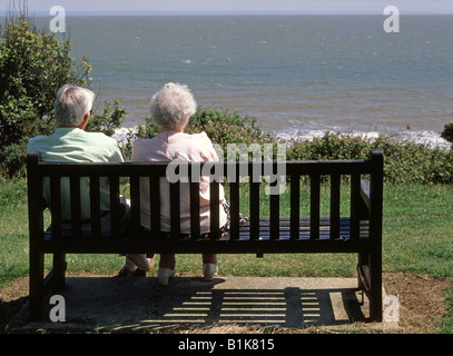 Rückansicht von grauen Haaren Rentner reifen älteren Mann und Frau Paar sitzen auf Klippe Sitzbank Blick auf Meer Badeort Essex England UK Stockfoto