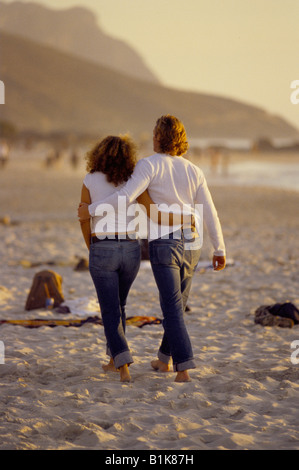 Junges Paar gehen Arm in Arm nach unten Camps Bay Strand Südafrika bei Sonnenuntergang tragen passende Kleidung. Brendan Bell Stockfoto