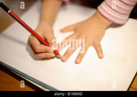 Mädchen im Alter von vier Jahren zieht um ihre Hand mit Bleistift auf Papier Stockfoto