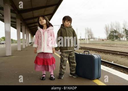 Jungen im Alter von sechs und Schwester im Alter von vier warten auf den Zug auf der Plattform am Bahnhof von Palmerston North New Zealand Stockfoto