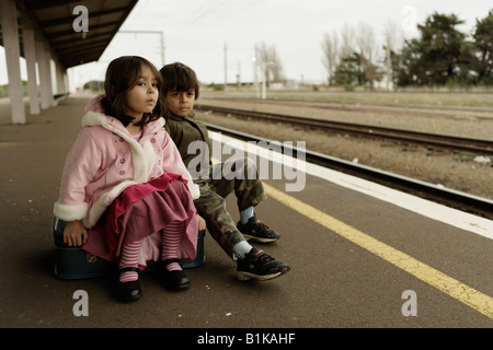 Jungen im Alter von sechs und Schwester im Alter von vier warten auf den Zug auf der Plattform am Bahnhof von Palmerston North New Zealand Stockfoto