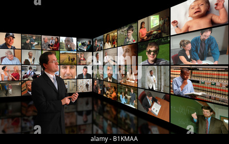 Mann, die high-Definition video global Media Kommunikationskanäle auf Wand-Bildschirme anzeigen Stockfoto