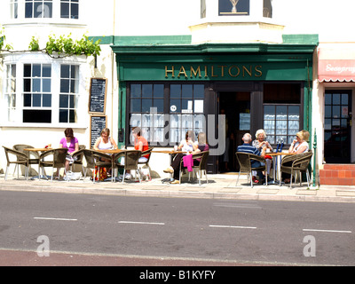 Gäste genießen eine Mahlzeit und Unterhaltung im Freien auf der Promenade in Weymouth, Dorset, England. Stockfoto