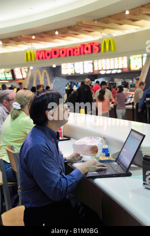 Ethnischer Passagier arbeitet auf Laptop-Computer in Fast-Foodcourt am internationalen Flughafen Orlando Florida Stockfoto