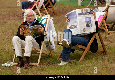 Mann liest Magazine und Frau liest Zeitung setzte sich in Liegestühlen bei The Guardian Hay Festival 2008 Hay on Wye Powys Wales UK Stockfoto