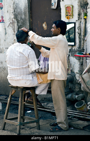 Indien-MUMBAI-Barber Shop bestehend aus einem Stuhl und Spiegel entlang einer Straße in Mumbai mit ein Barbier rasiert einen Mann Stockfoto
