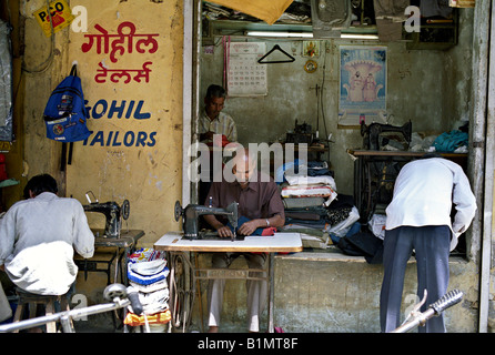 Indien MUMBAI MAHARASHTRA Schneider arbeitet an Nähmaschinen eingerichtet, auf dem Bürgersteig vor einem kleinen Laden auf dem Markt in Mumbai Stockfoto