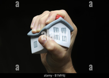 MUSTERHAUS DRÜCKTE UND HIELT IN A MANS HAND RE GEHÄUSE MÄRKTE HYPOTHEKEN WIRTSCHAFT IMMOBILIEN IMMOBILIEN AGENTEN HOME KÄUFER PREISE UK. Stockfoto