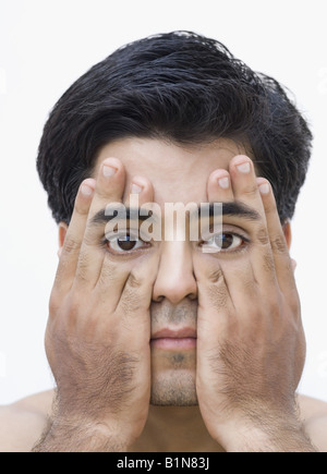 Porträt eines jungen Mannes, der seine Augen mit den Händen bedecken Stockfoto