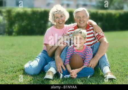 Porträt eines jungen halten Fußball posiert auf Rasen mit Großeltern Stockfoto