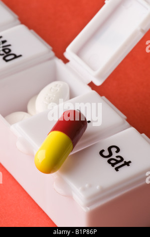 Einige Pillen und Tabletten in einem offenen Pillbox auf einen orange Hintergrund Stockfoto