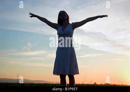 Frau Silhouette stehen im Feld bei Abenddämmerung Arme angehoben, Sonne Stockfoto