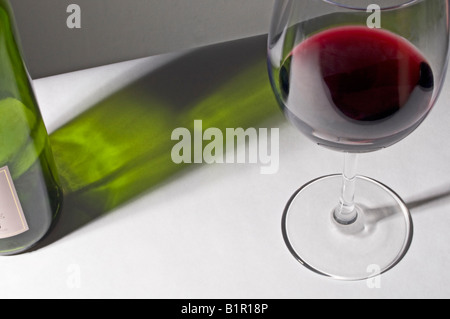 Glas und Flasche Rotwein mit Schatten Stockfoto