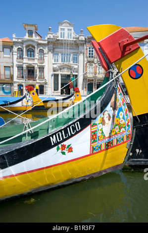 Traditionell bemalten Fischerboote in Aveiro, Portugal mit reich verzierten Gebäuden des alten Hafens im Hintergrund. Stockfoto