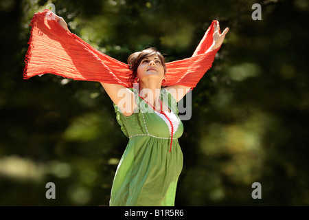 junge schöne schwangere Frau mit den Händen oben in der Luft in der Natur Stockfoto