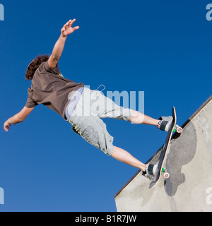 Teenboy hat Tricks in der Halfpipe an einen Skate-park Stockfoto