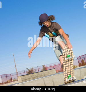 Teenboy hat Tricks in der Halfpipe an einen Skate-park Stockfoto