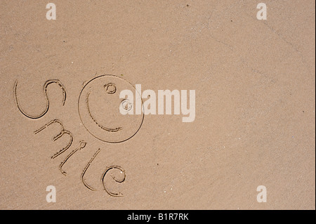 Lächeln und Gesicht im Sand am Strand Stockfoto