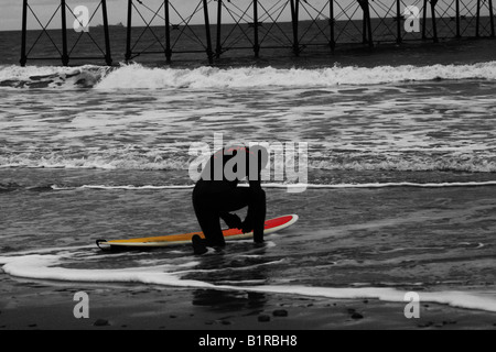 Einsamer Surfer schwarz / weiß Bild mit farbigen Surfer im viktorianischen Toan Saltburn am Meer Cleveland Stockfoto