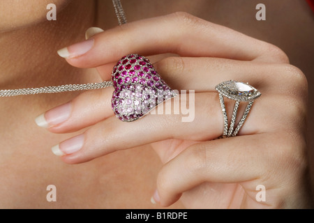 Eine Frau mit einem Edelstein besetzt Halskette in Herzform während des Tragens eines brillant-Diamant-Ring. Stockfoto