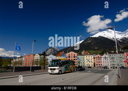 Gebäude in einer Reihe auf Mariahilfer Straße hinter einem Bus über eine Brücke über den Inn Schnee bedeckte Berge der Alpen Stockfoto