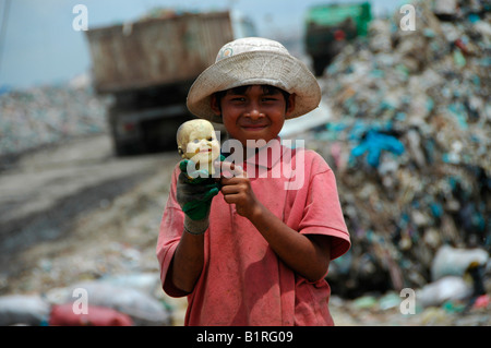 Kind beim Stöbern durch eine Müllhalde findet eine Puppen-Kopf auf der Stung Meanchey kommunalen Mülldeponie im Süden von Kambodscha Stockfoto