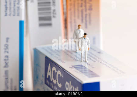 Tablet-Boxen und Miniatur-Sanitäter tragen eines Patienten auf einer Bahre, symbolische Foto Stockfoto