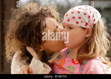 Mutter mit dem lockigen Haar, küssen ihre Tochter, 8 Jahre alt Stockfoto