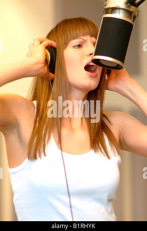 Junge Frau mit Leidenschaft singt in ein Mikrofon in einem Tonstudio Stockfoto