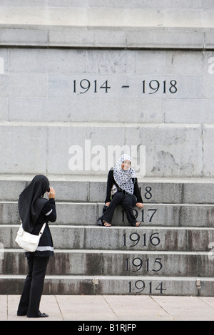 Zwei muslimische Frauen fotografieren einander vor der Kenotaph, Kriegerdenkmal St. Andrews Road, Singapur, Südostasien Stockfoto