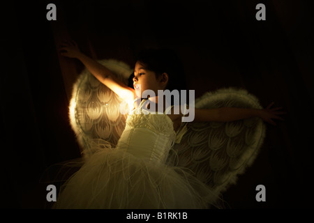 Mädchen im Alter von vier Engel Kostüm von Seite von Taschenlampe beleuchtet Stockfoto