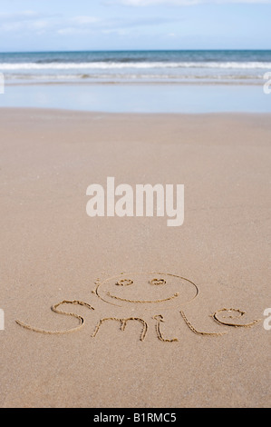 Lächeln und Gesicht im Sand am Strand Stockfoto