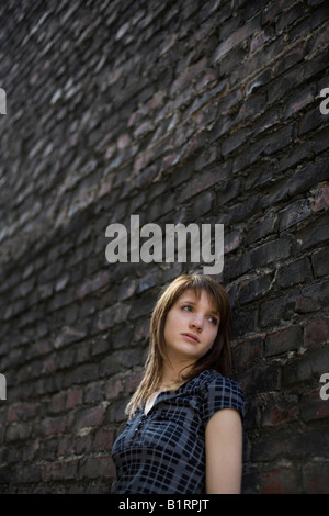 Junge Frau mit verlassenen Ausdruck eine dunkle Mauer gelehnt Stockfoto