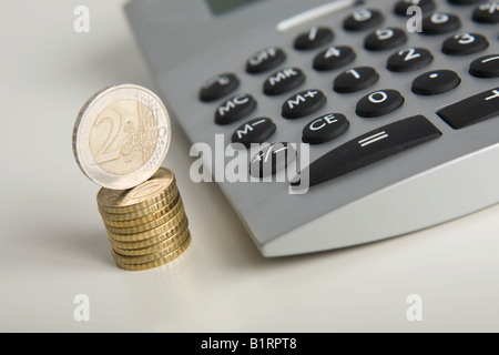 Euro-Münzen neben einem Rechner gestapelt Stockfoto