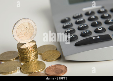 Euro-Münzen neben einem Rechner gestapelt Stockfoto