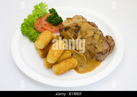 Schweinsfilet und sautierten Pilzen in Sahne-Sauce serviert mit Kroketten Stockfoto