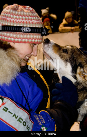 Junge Frau Kuscheln ein Schlittenhund, Yukon Quest Schlittenhunderennen zu beenden, Whitehorse, Yukon Territorium, Kanada Stockfoto