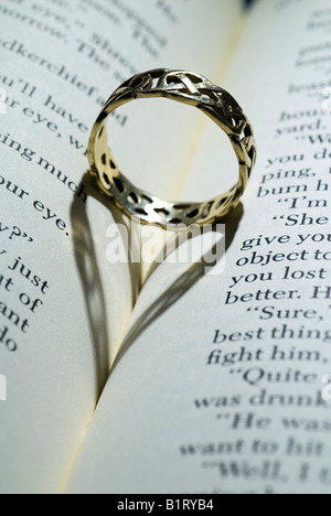Ring mit herzförmigen Schatten auf ein offenes Buch liegend